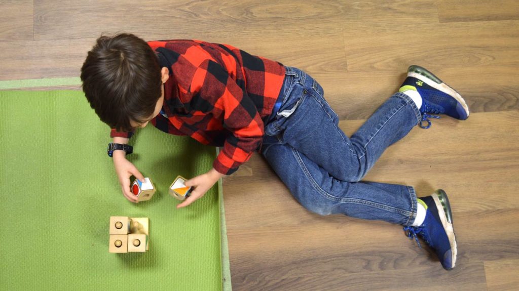 A little boy playing with blocks on a green mat