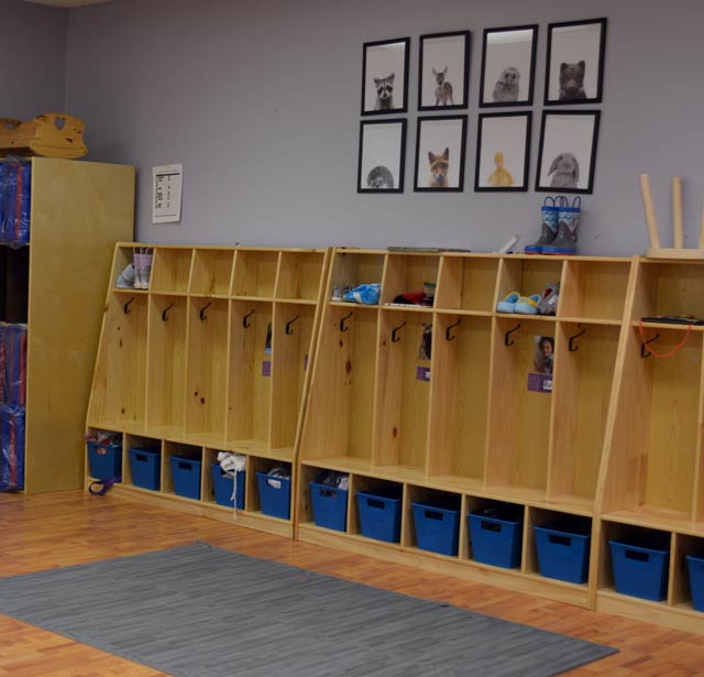 A series of cubbies and blue bins in a classroom.